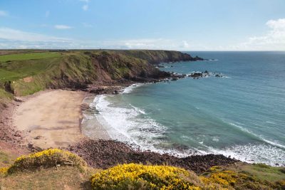 view looking down from the airfield with gorse on the cliffs, a blue sea and blue sky
