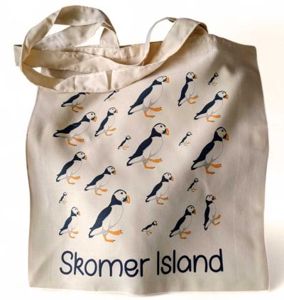cream coloured shopping tote with graphic design puffins covering the front and the words skomer island